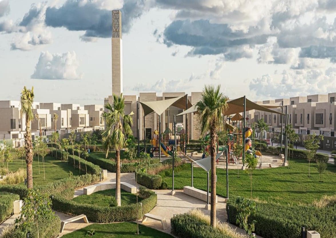 حديقة منسقة بمظلات شراعية وأشجار نخيل في مجمع جدن الفرسان